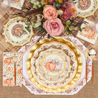 A fall-themed table setting features the Turkey & Gourds Table Setting Bundle by Sophistiplate LLC, including designer disposable plates adorned with turkey and gourd motifs, gold cutlery, plaid and burlap placemats, and a floral centerpiece with pink roses and autumnal blooms. The distinctive turkey design appears on both the top plate and matching napkin.