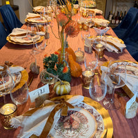 A Sophistiplate LLC Turkey & Gourds: Thanksgiving Table for 16 set on a mauve tablecloth with velvet ribbons, gourds, and floral centerpieces.